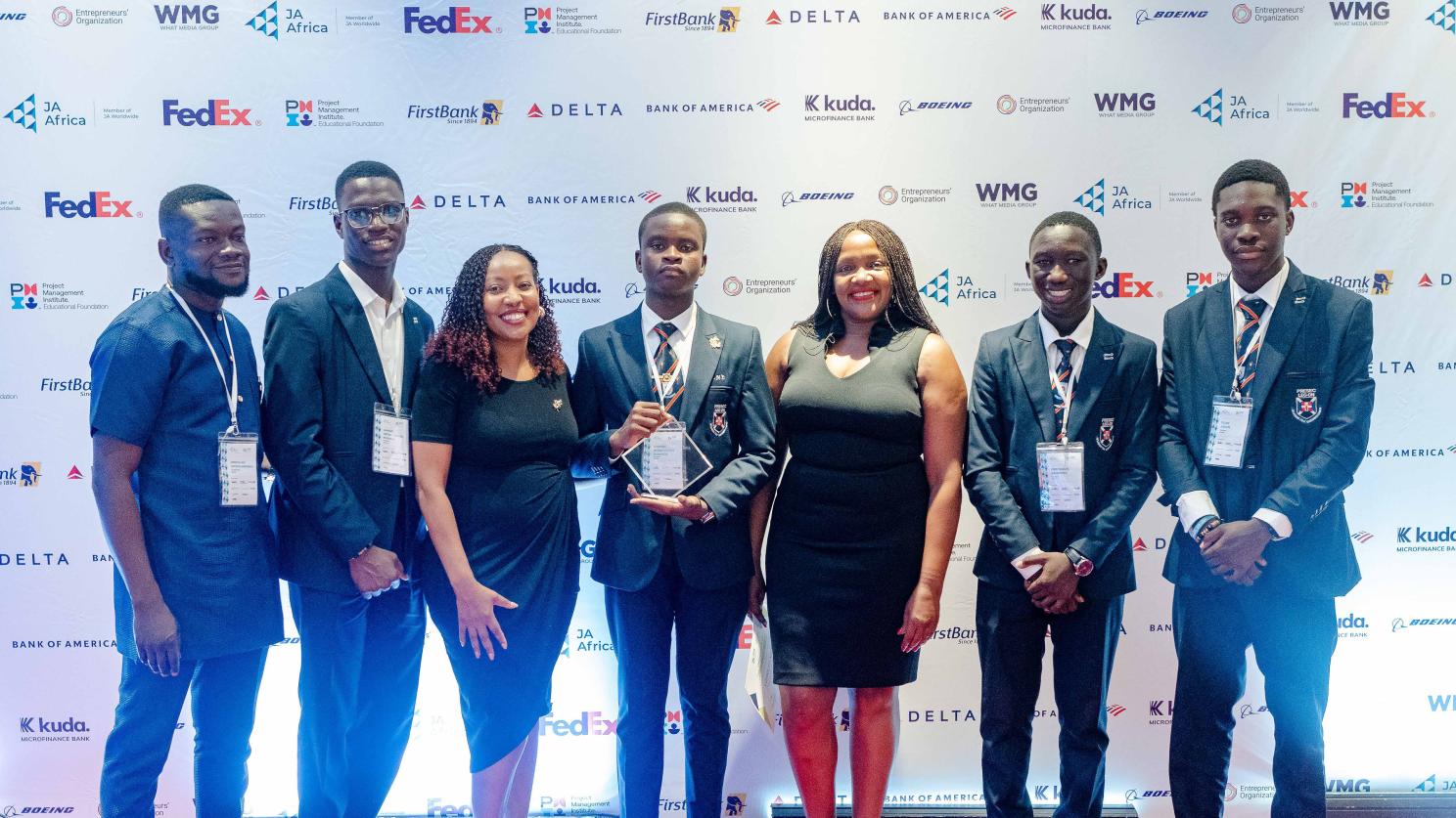 Group photo with person in the center holding an award
