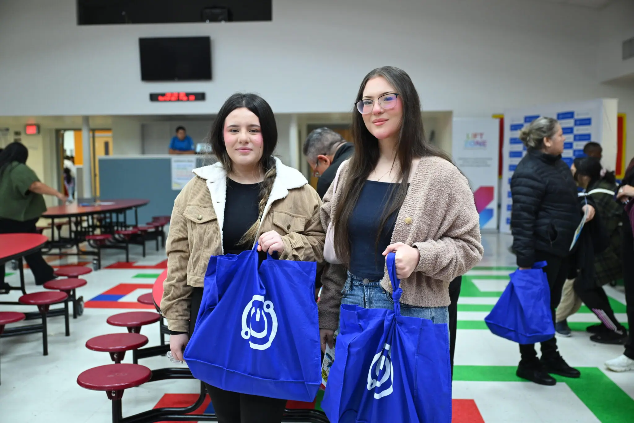 Two students holding blue bags of tech supplies
