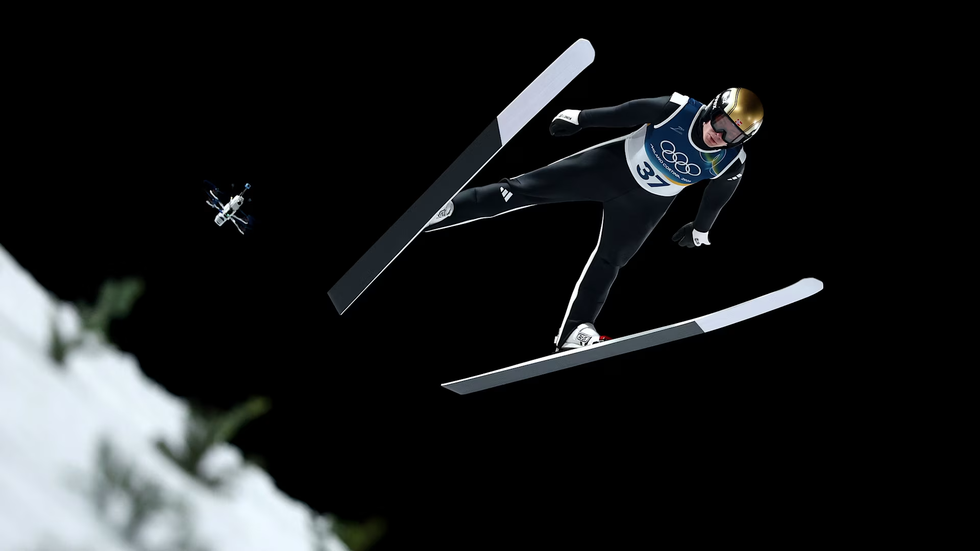 skier flying through the air with a drone nearby