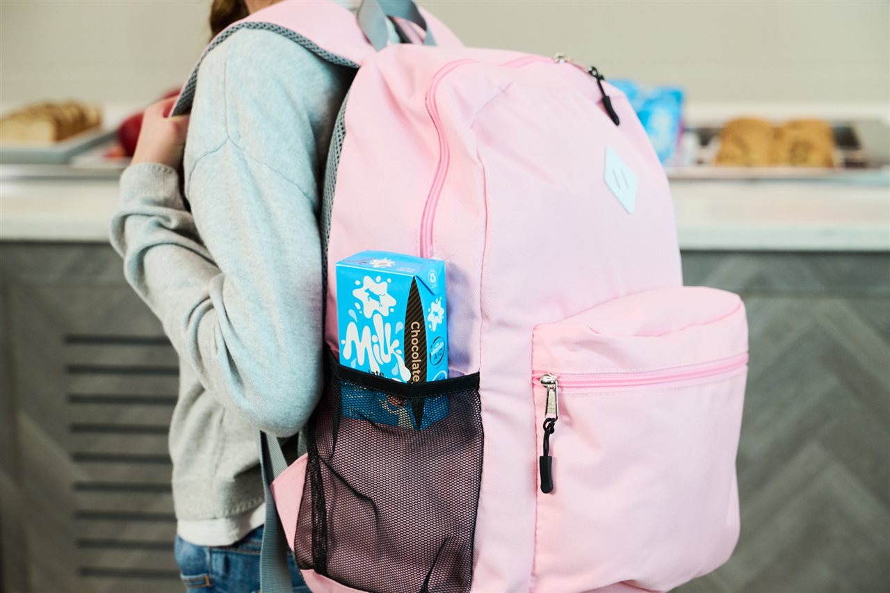 A single serving container of milk in a child's backpack