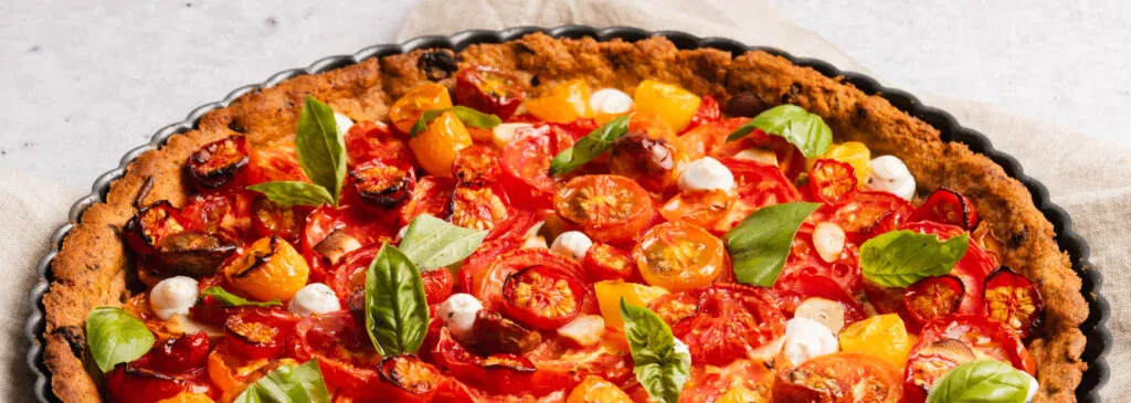 tart filled with cherry tomatoes, cheese, and basil