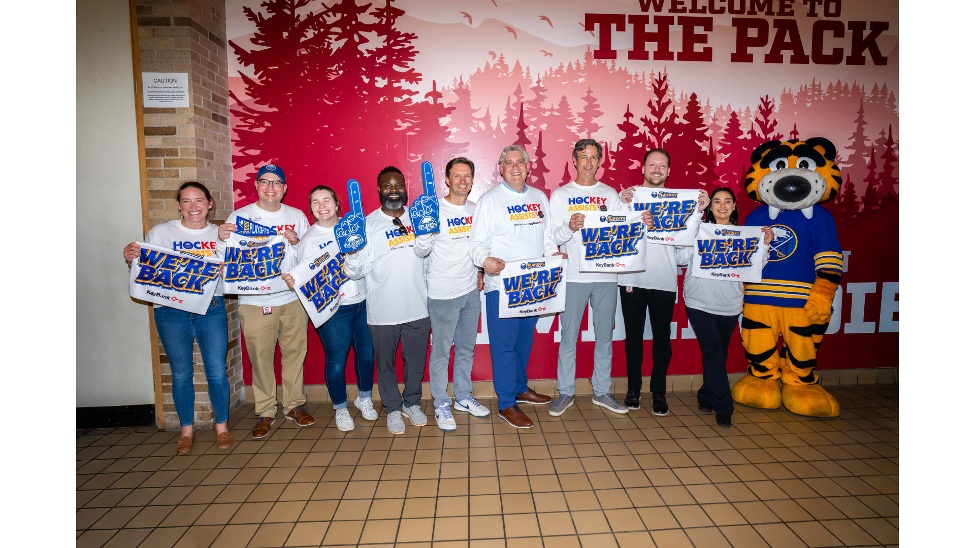 A group holding up "we're back" banners, alongside Sabres mascot