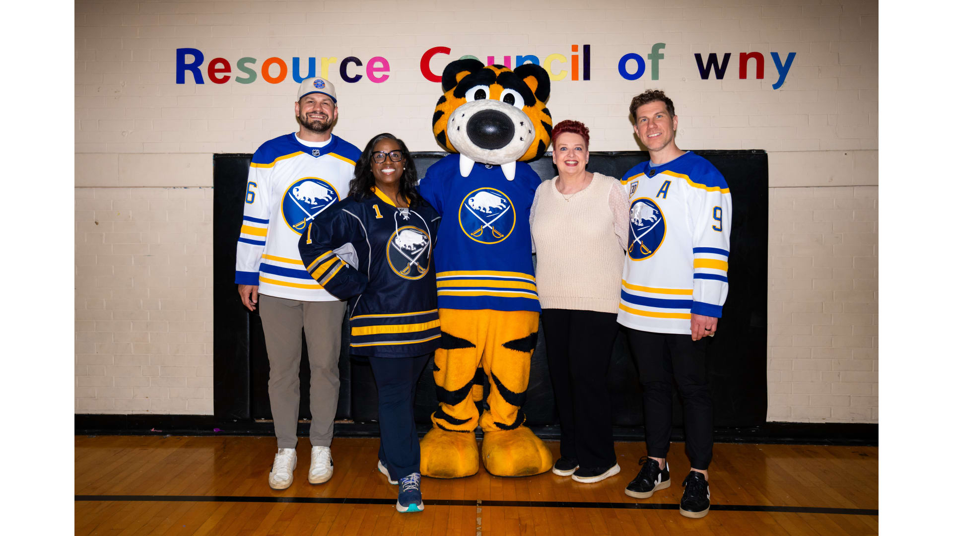 Four people posing with mascot
